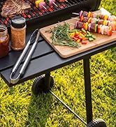 Scène de grillades en plein air avec grill de table noir avec planche à découper en bois avec brochettes et légumes frais, boisson en verre, sur fond d'herbe verte.