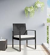 avec structure tissée foncée, assise en coussin et accoudoirs blancs. Situé contre un mur lumineux avec des plantes en fleurs visibles.