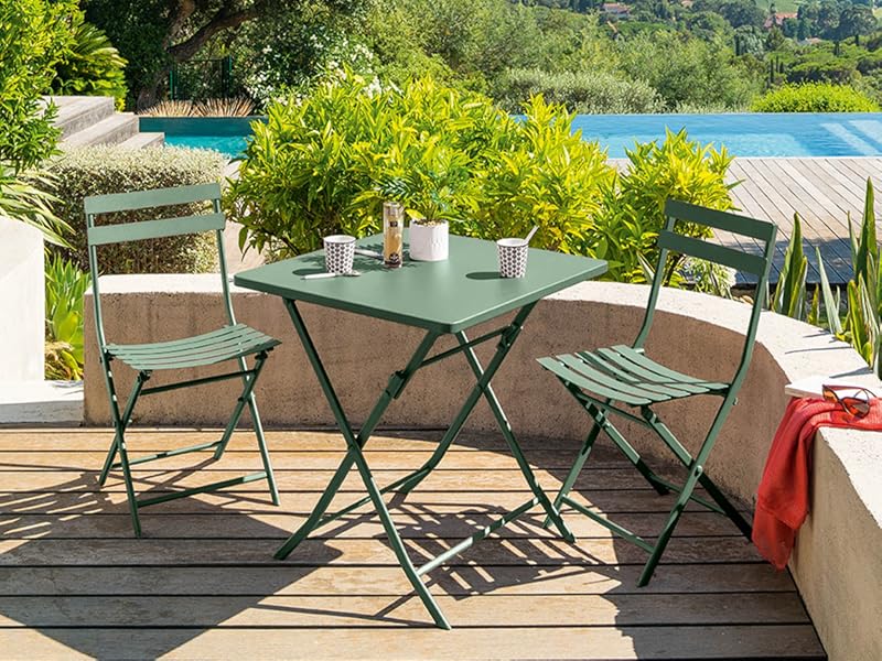 avec table et chaises en métal vert donnant sur une piscine et une vue panoramique sur la côte, entouré d'une végétation luxuriante.