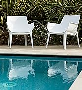 Deux fauteuils d'extérieur blancs au design moderne et épuré, placés près du bord d'une piscine entourée de plantes vertes luxuriantes