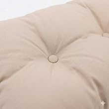 Coussin ou oreiller matelassé beige avec motif en losange capitonné et boutons apparents, présentant une texture de tissu neutre et une surface dimensionnée.