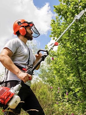 utilisé à l'extérieur, doté d'équipements de protection, notamment un casque orange avec écran facial et protection auditive. Équipement illustré en train de tailler de hautes haies