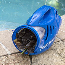 un seau bleu avec une poignée bleue se trouve à côté d'une piscine.