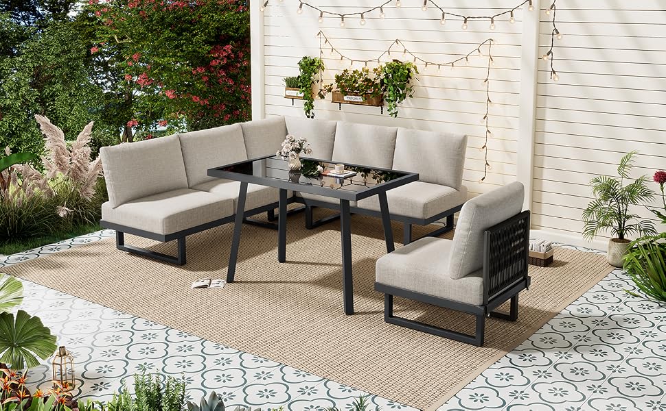 Arrangement de meubles de patio extérieur comprenant un canapé sectionnel beige avec une table d'appoint assortie et une table basse à cadre noir sur une surface pavée avec fond de jardin.