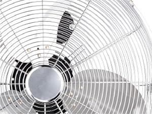 Image rapprochée en noir et blanc de la grille avant et du moyeu central d'un ventilateur électrique, montrant un motif de fil de protection circulaire