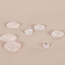 Plusieurs gouttelettes d'eau claire de différentes tailles disposées sur une surface de sable beige ou de poudre, créant une composition épurée et minimaliste avec des ombres claires.