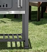 Châssis d'un camping-car ou d'une remorque montrant des poteaux de support noirs et un escabeau sur de l'herbe verte, démontrant le système de support structurel.